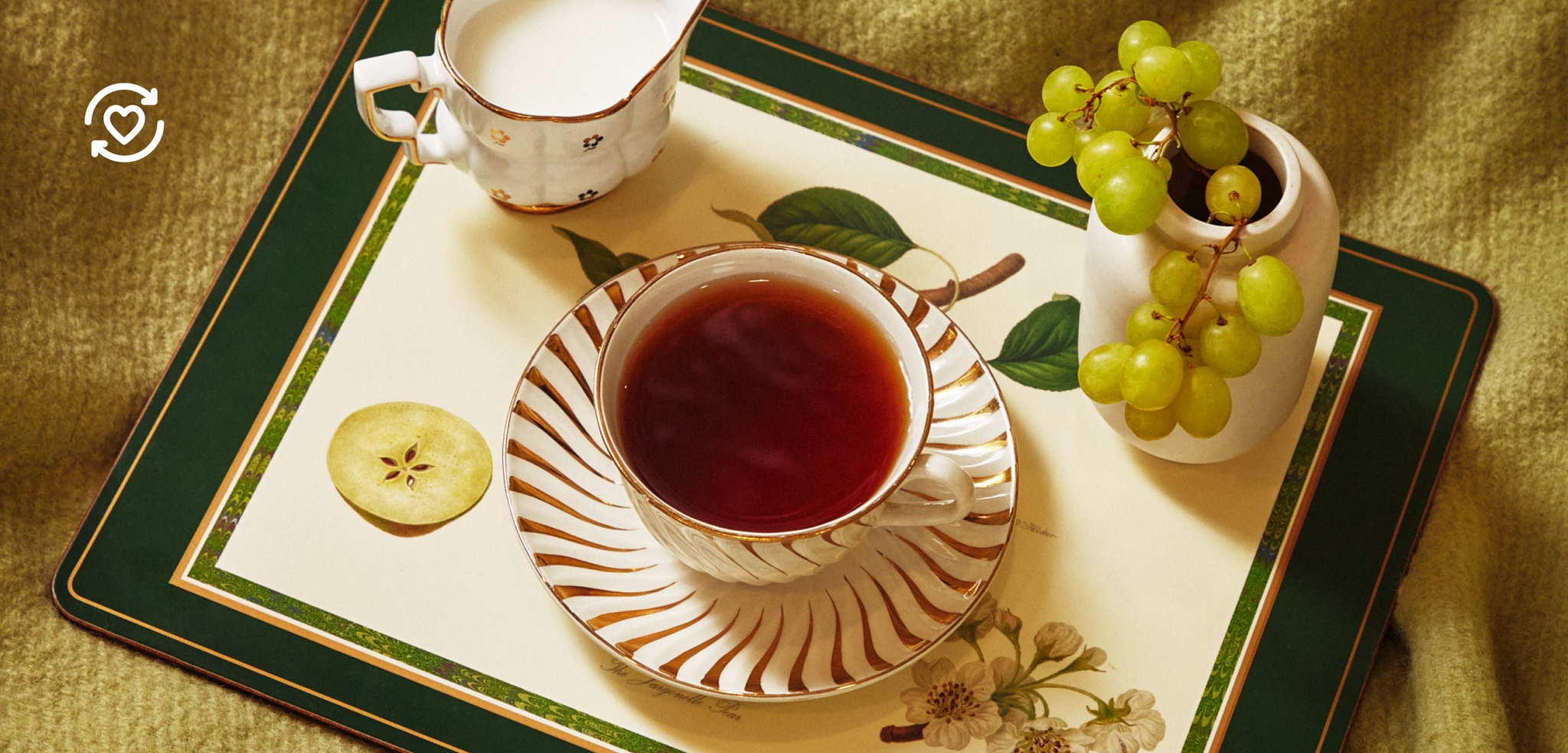 En tekopp och en liten mjölkkanna på en blommig bricka