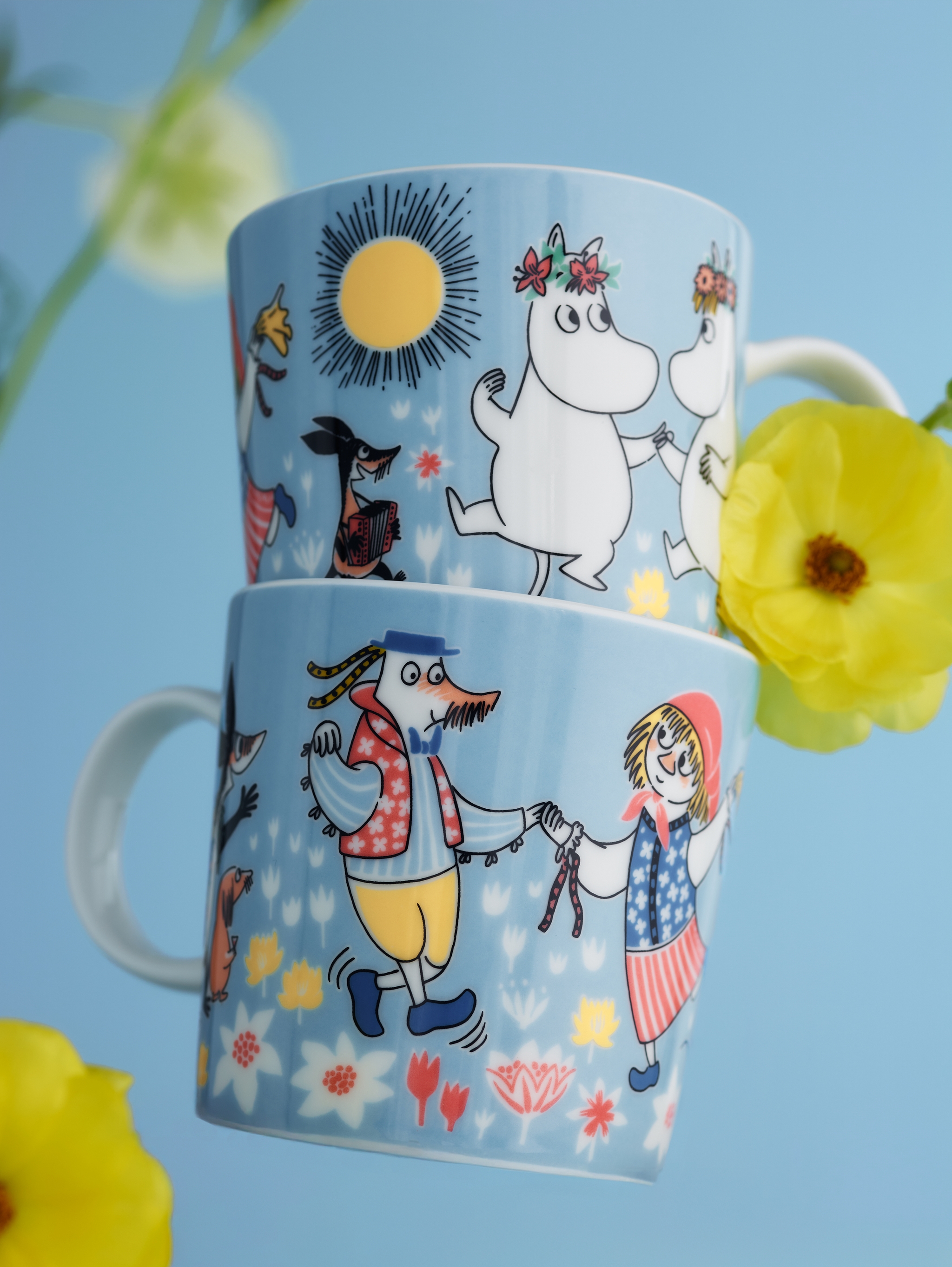 A wooden dining table is set with pink and green Moomin-themed tableware, illuminated by warm sunlight.