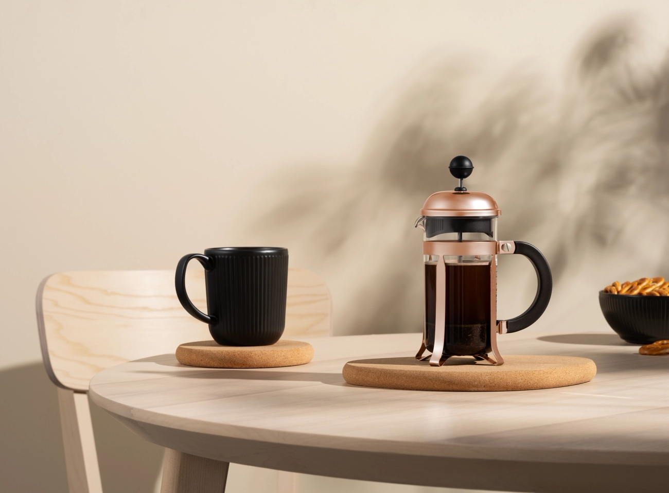 Ranskalainen pressopannu on puisella pöydällä kupin kahvin vieressä.