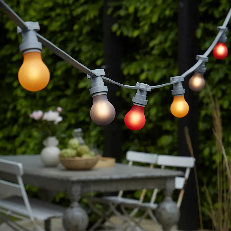 En lyslenke henger over et bord med stoler