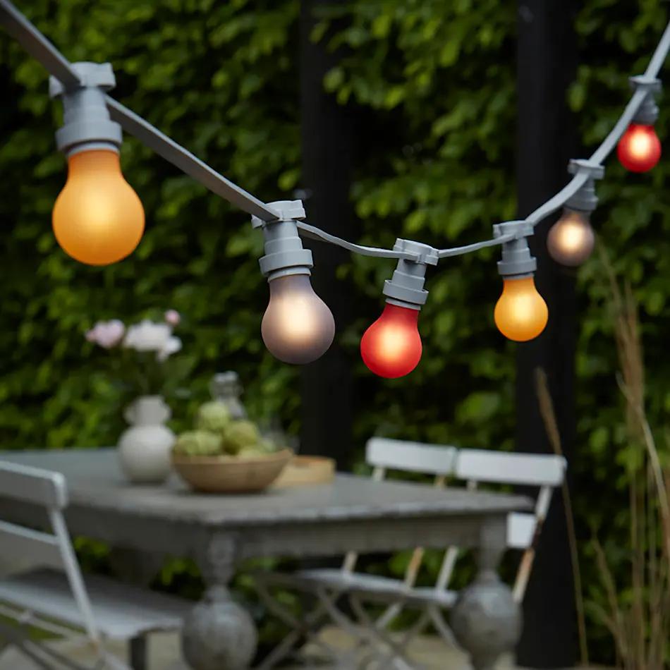 En lyslenke henger over et bord med stoler