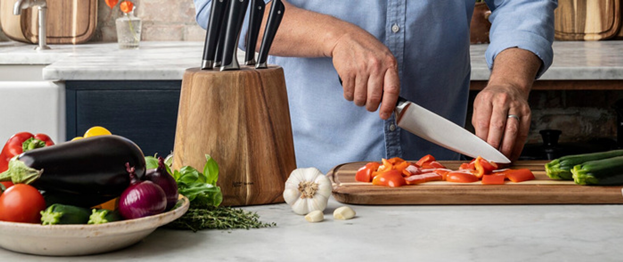Ulike grønnsaker og en kniv som skjærer paprika