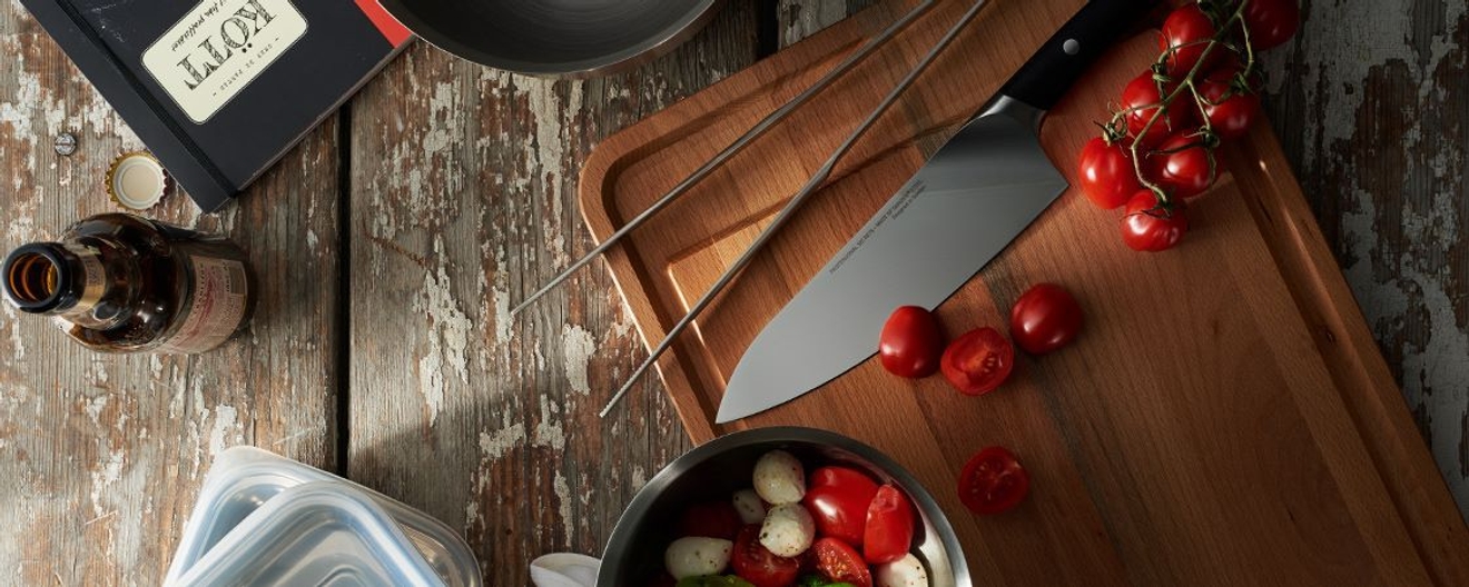 Trancherbrett med rille i. Tomater og kniv på benk