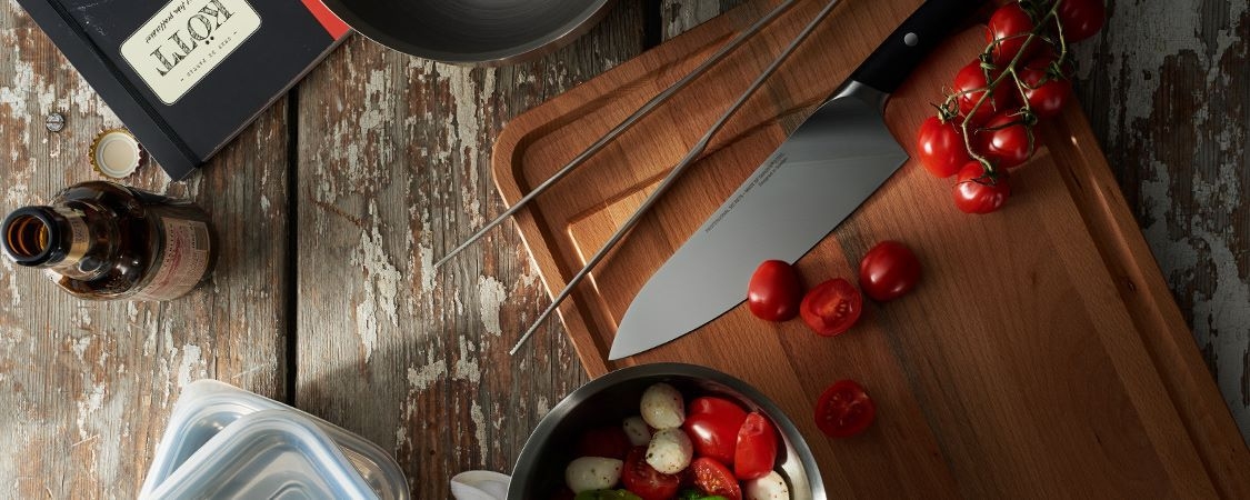 Trancherbrett med rille i. Tomater og kniv på benk