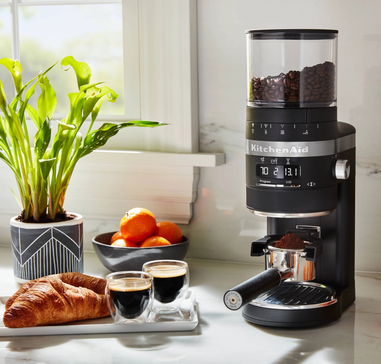 Kaffekvarn svart från Kitchenaid med nybryggd espresso och croissant