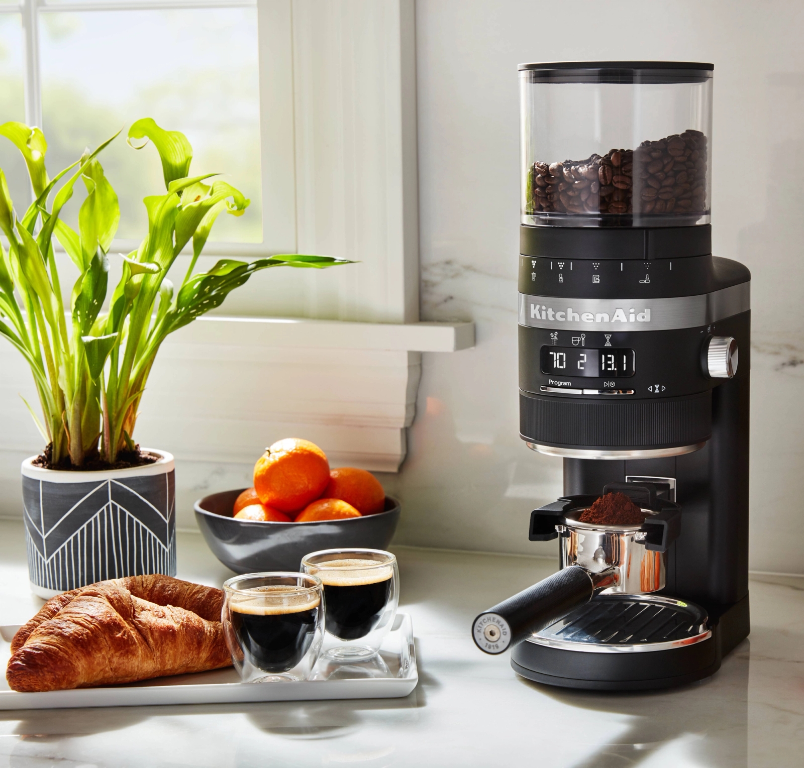 Kaffekvarn svart från Kitchenaid med nybryggd espresso och croissant