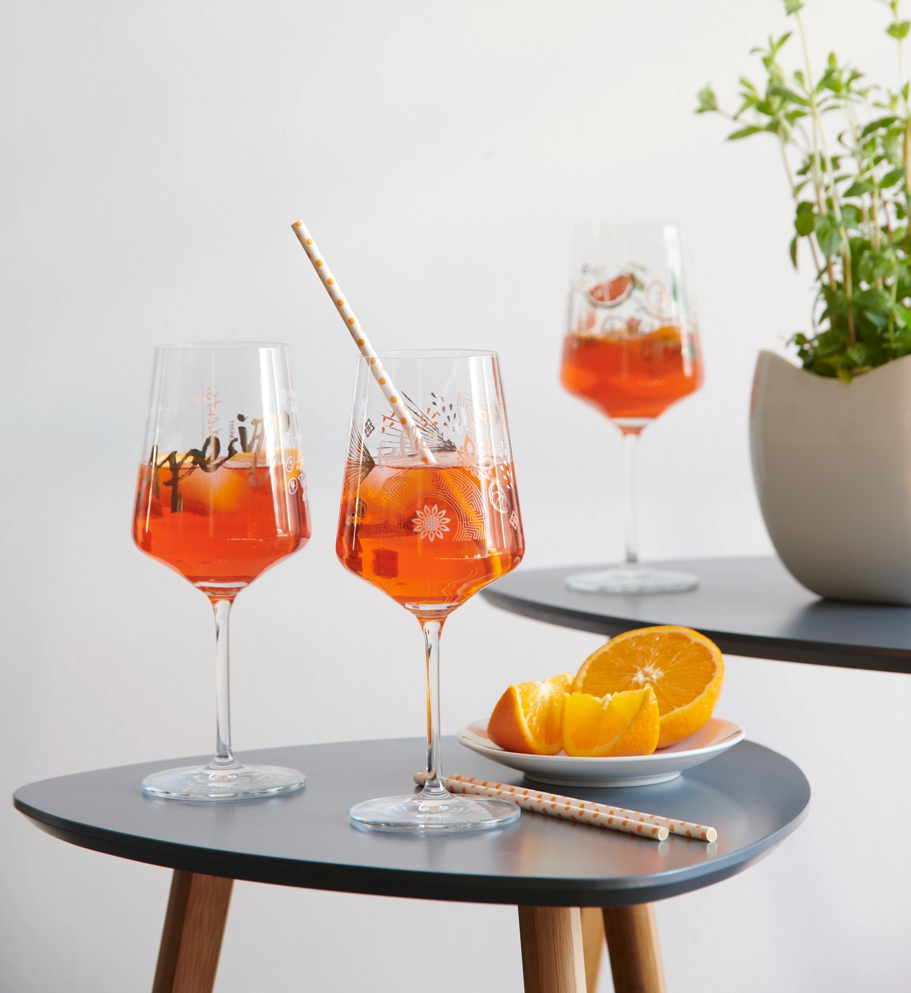 Aperol spritz glas på ett litet satsbord med apelsiner i en skål
