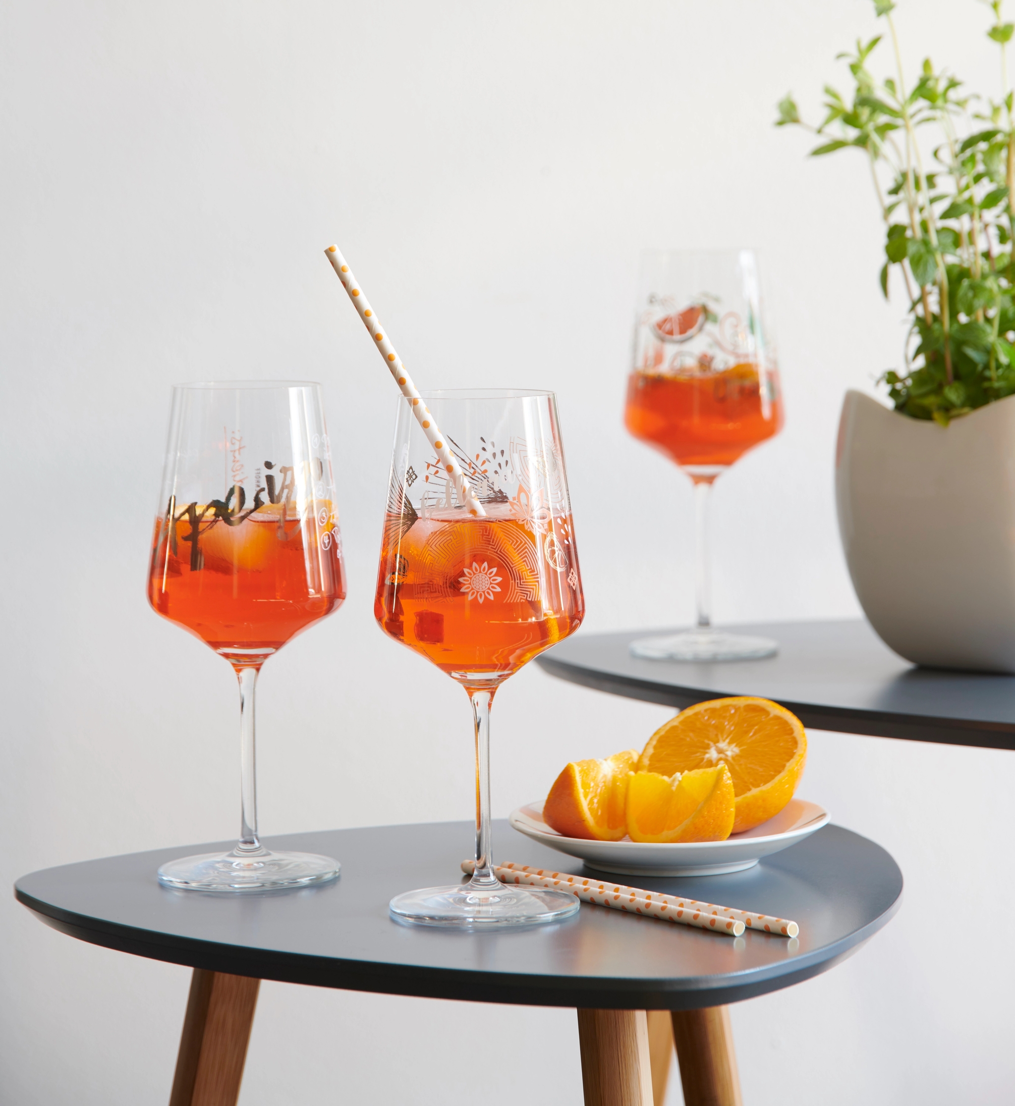 Aperol spritz glas på ett litet satsbord med apelsiner i en skål