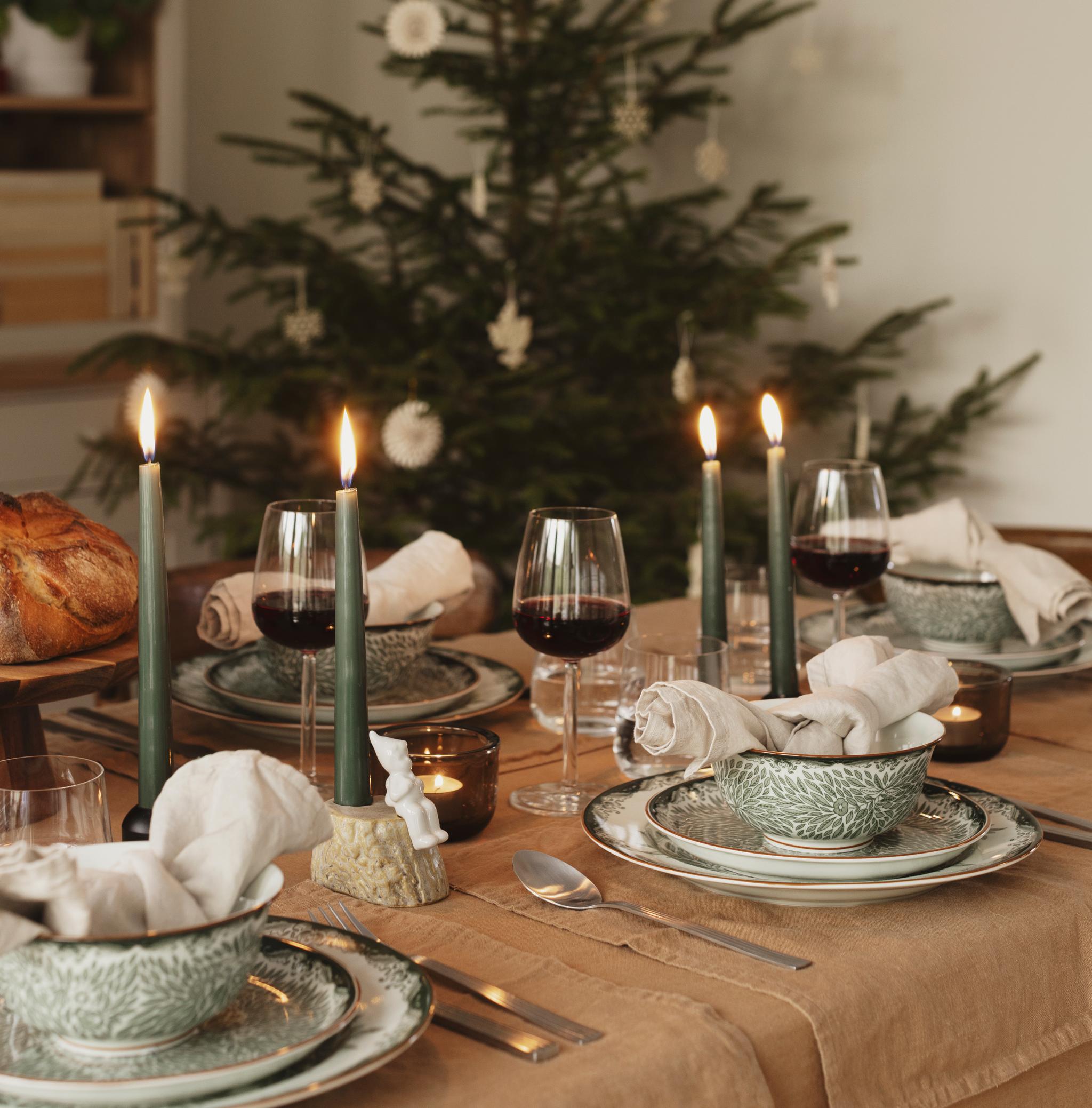a table set for a christmas dinner with a christmas tree in the background .