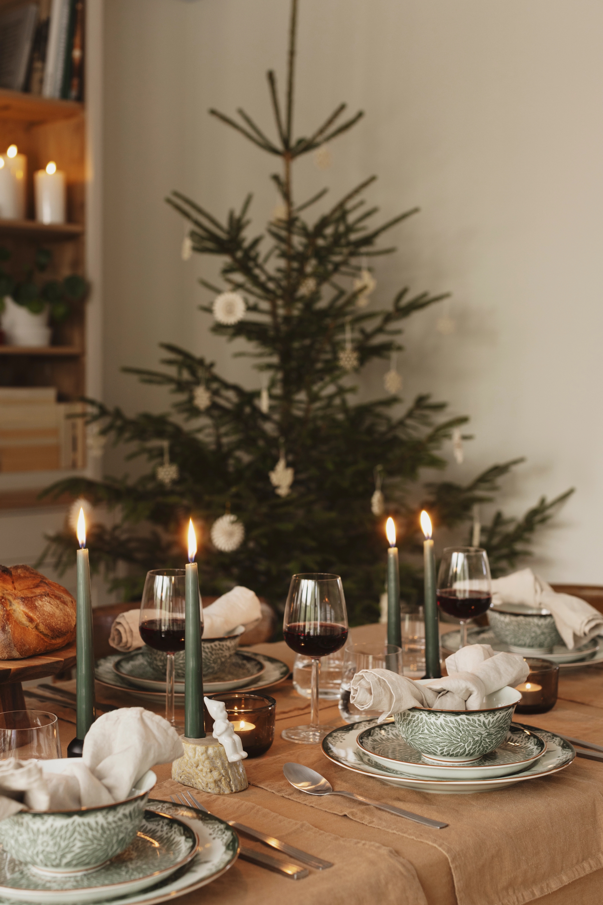 a table set for a christmas dinner with a christmas tree in the background .