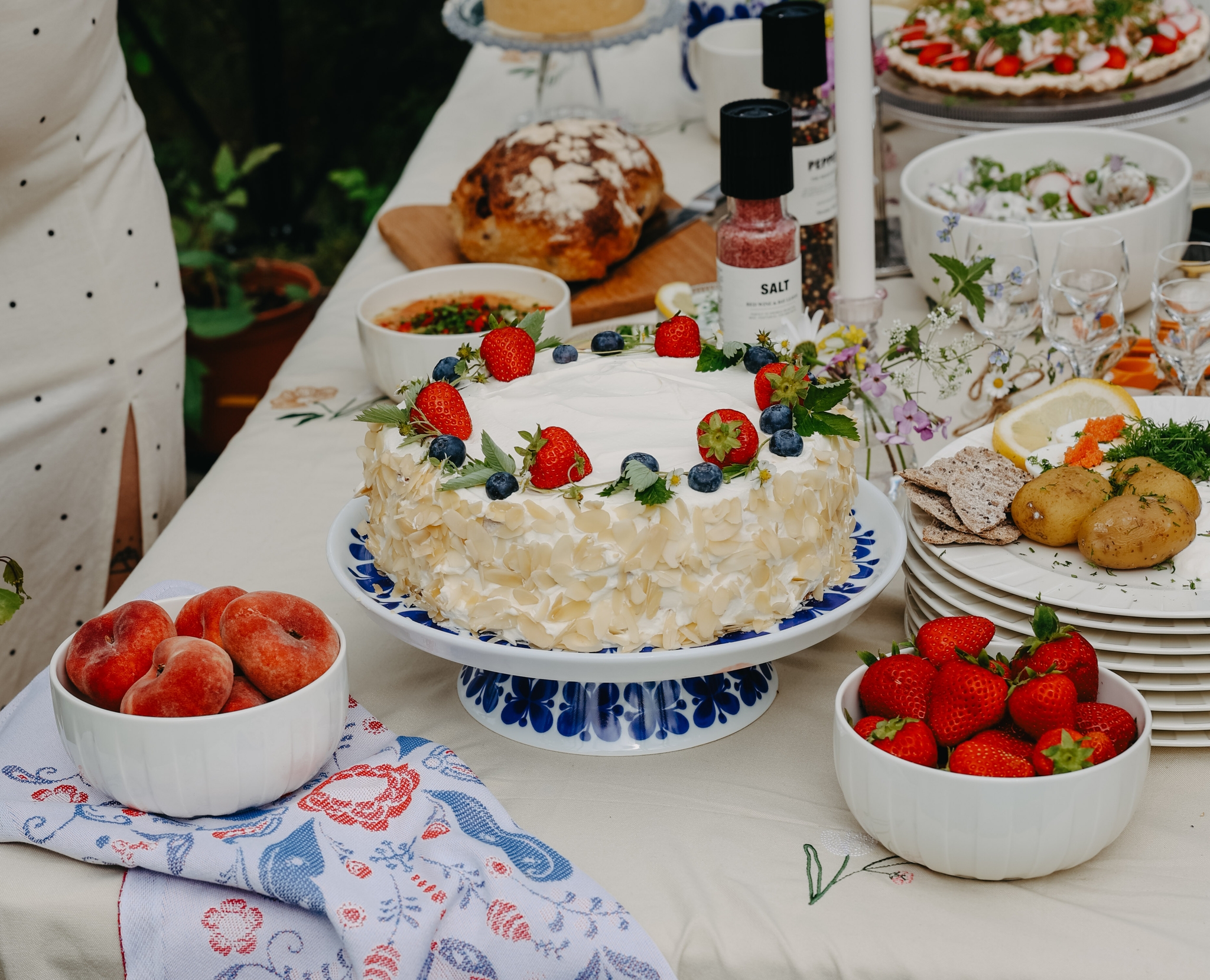 Somrig svensk festdukning utomhus med jordgubbstårta, färska bär och traditionella rätter på ett vackert dekorerat bord.