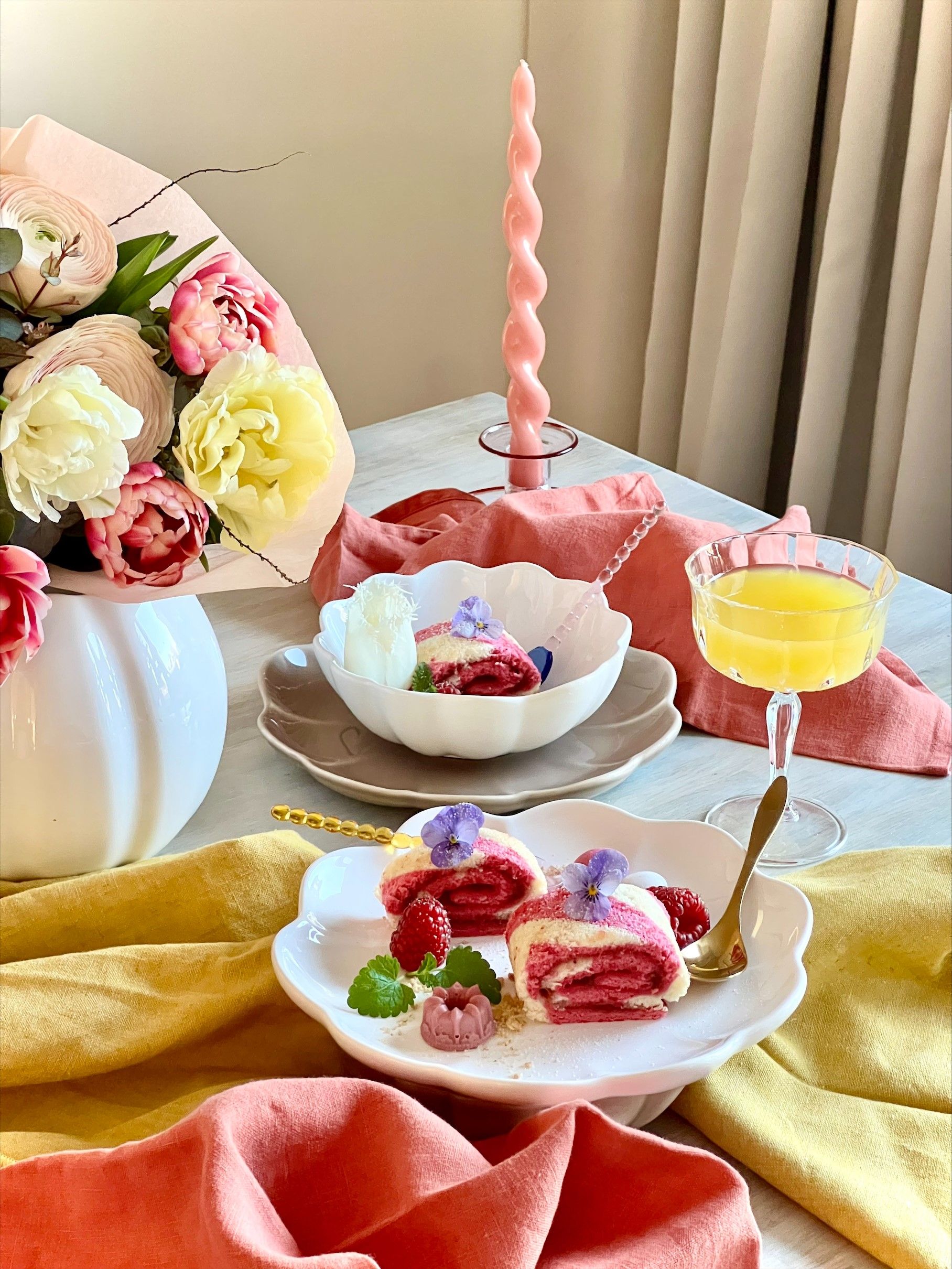 Rosa rulltårta med hallon på vit assiett