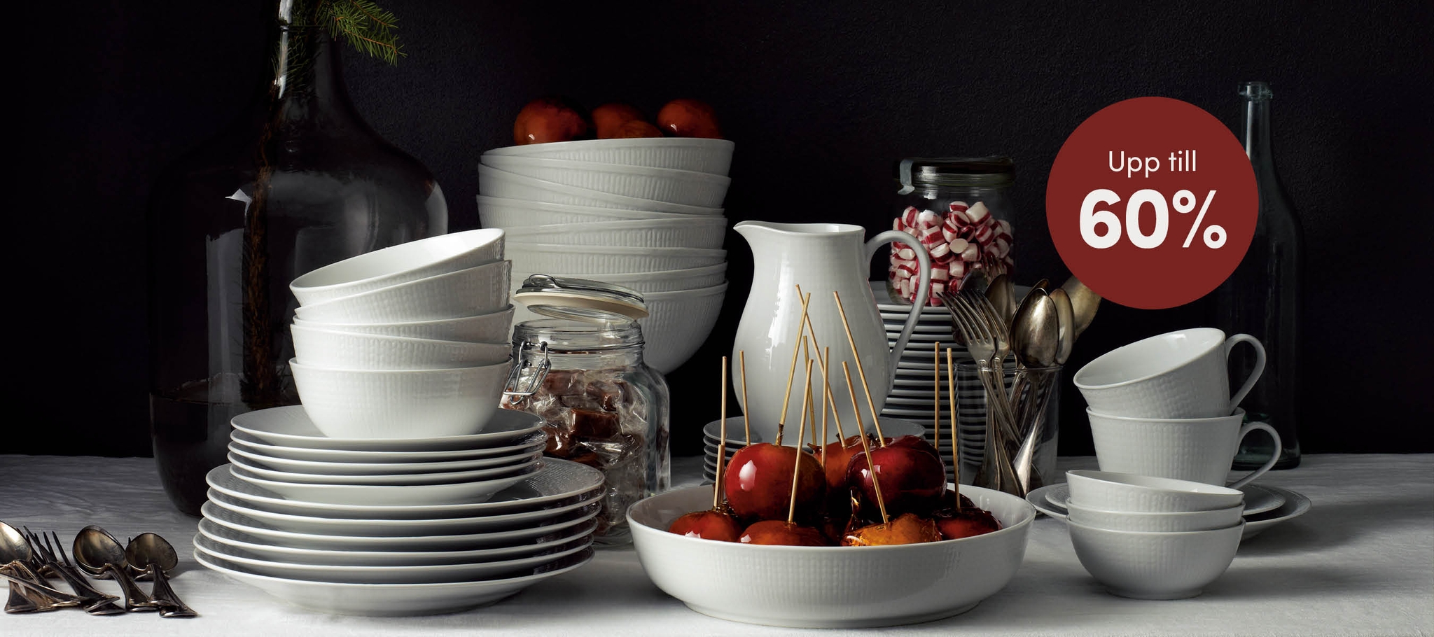 Vit dukning med röda äpplen och ett erbjudande med upp till 60% erbjudande