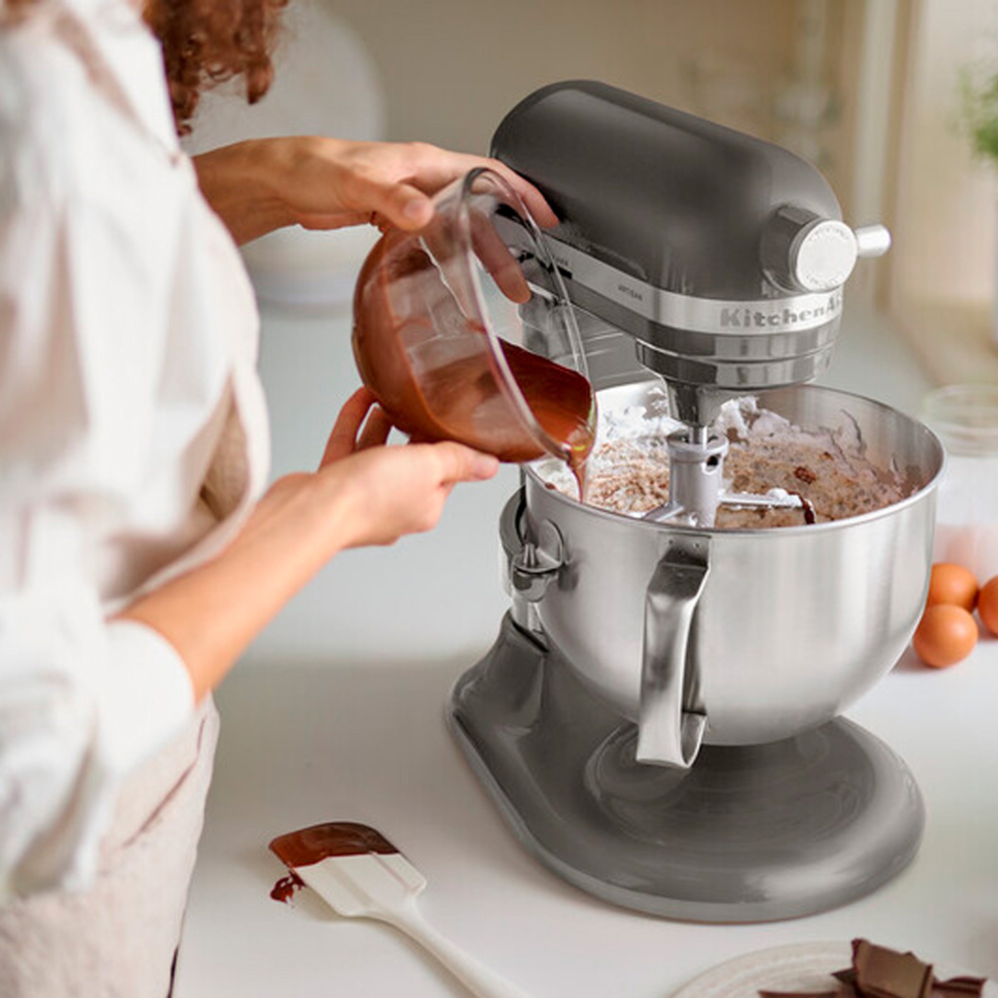 Person häller smet i en stående köksmaskin från KitchenAid på en köksbänk.