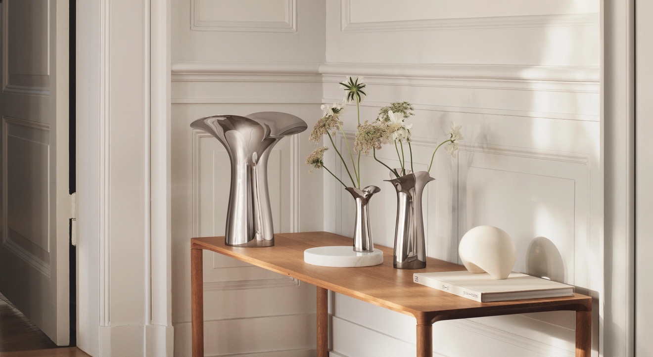 Georg Jensen vas i blankpolerat stål med skira blommor i på bord