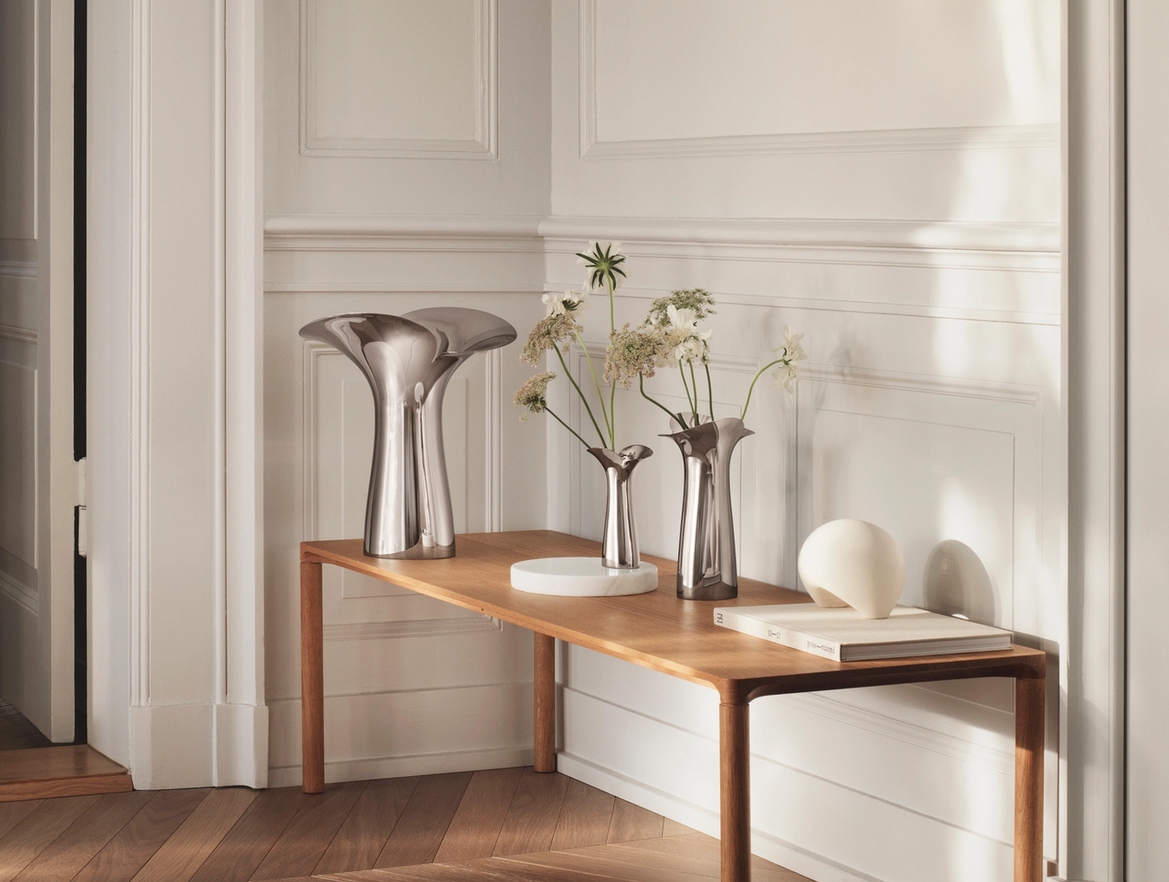 Georg Jensen vas i blankpolerat stål med skira blommor i på bord