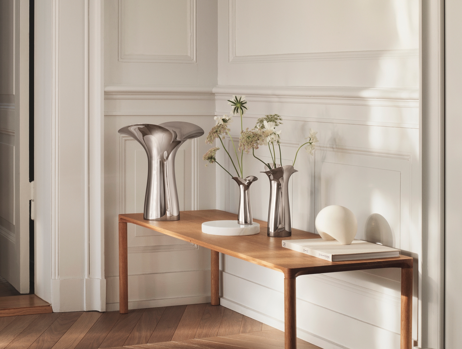 Georg Jensen vas i blankpolerat stål med skira blommor i på bord