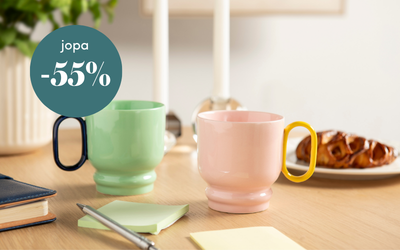 Värikkäät kahvimukit ja aamiaissämpylä puupöydällä, tarjouksena jopa -55 %.