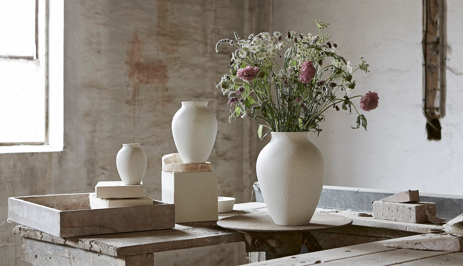 Sandfärgade krukor med gröna växter & vinröda blommor