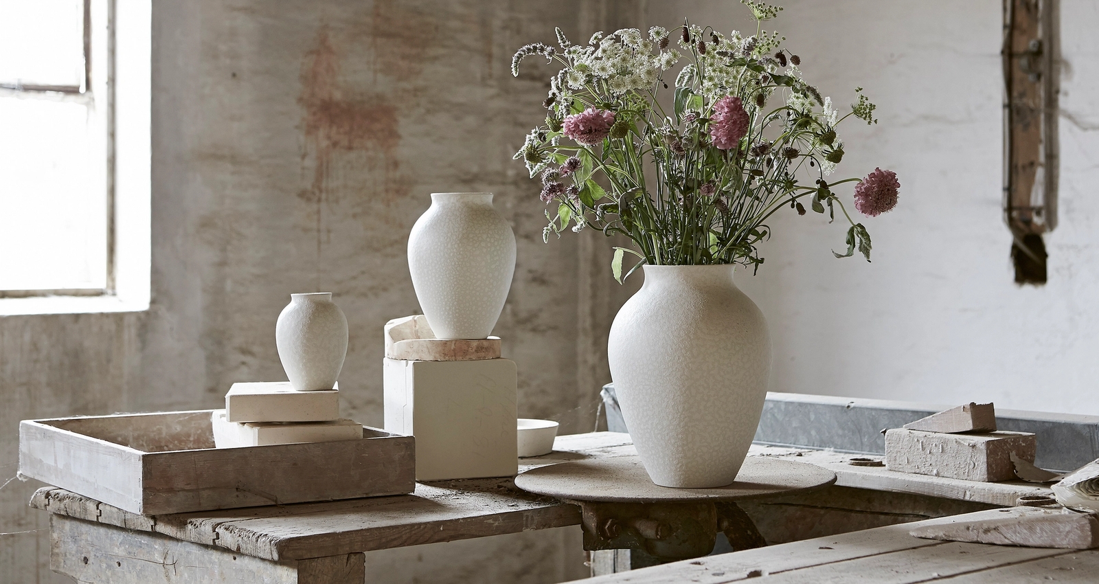 Sandfärgade krukor med gröna växter & vinröda blommor