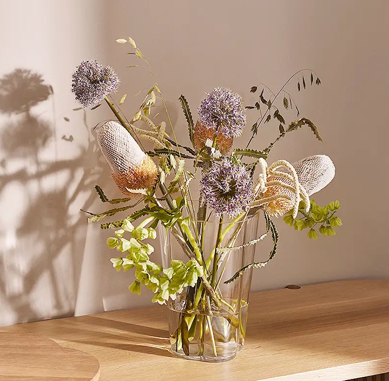 lasimaljakko kukkien kera puisella hyllyllä