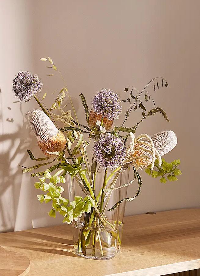 lasimaljakko kukkien kera puisella hyllyllä