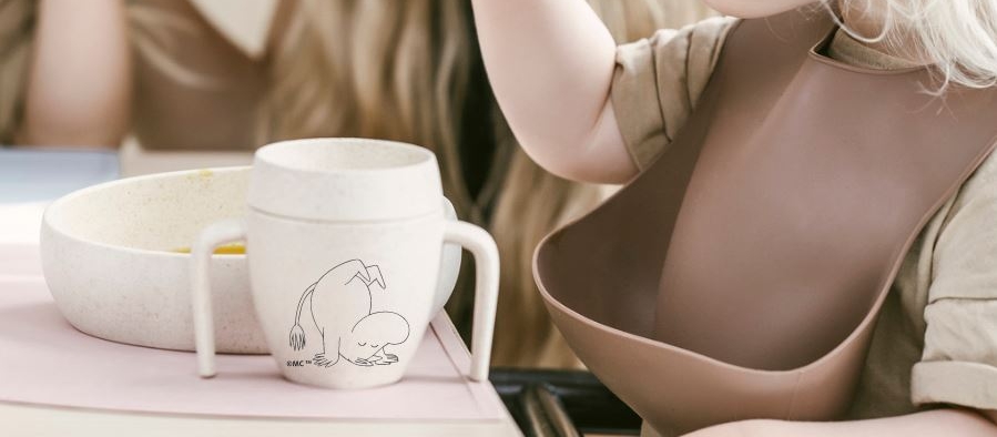 Skandio barnservis med mumin och ett litet barn som äter