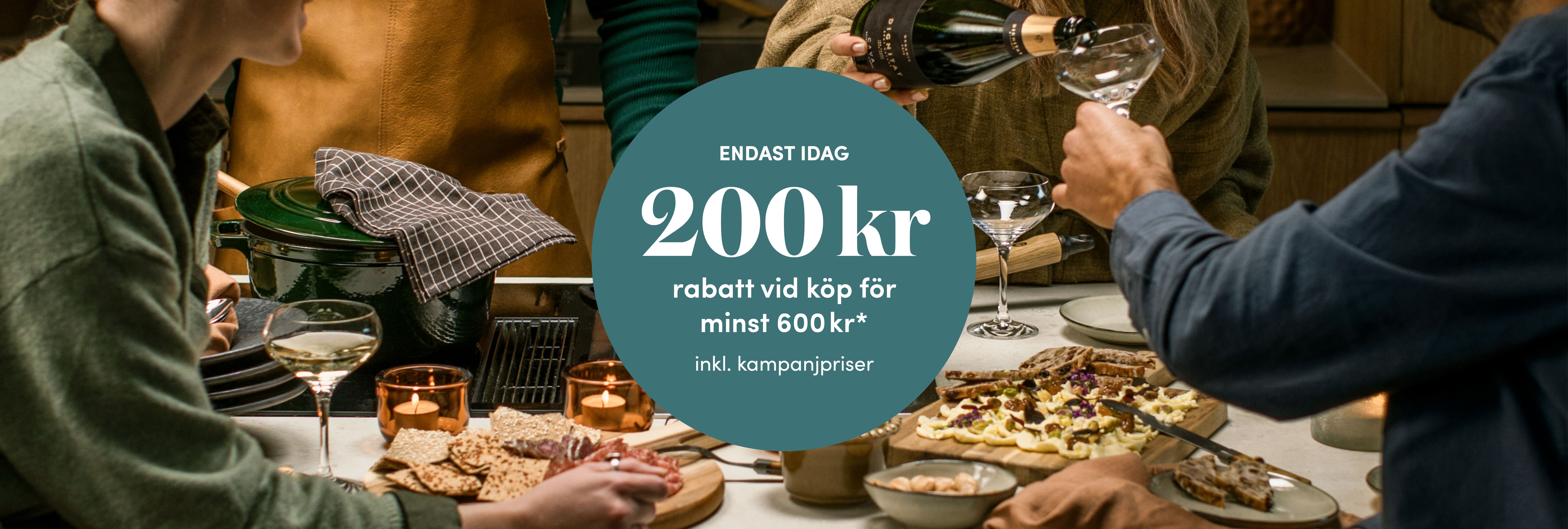 Vänner samlas kring en festlig middag med vin och erbjudandet 200 kr rabatt vid köp för minst 600 kr.