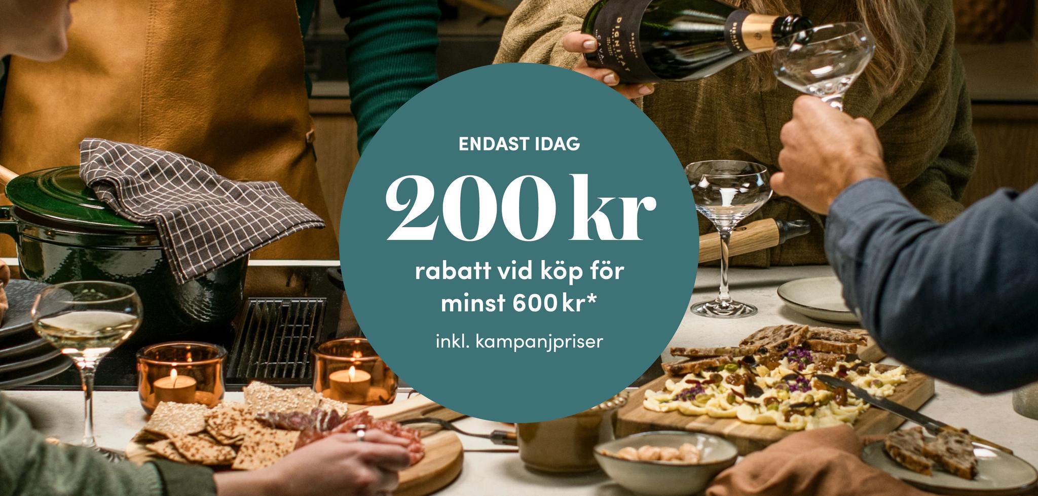 Vänner samlas kring en festlig middag med vin och erbjudandet 200 kr rabatt vid köp för minst 600 kr.