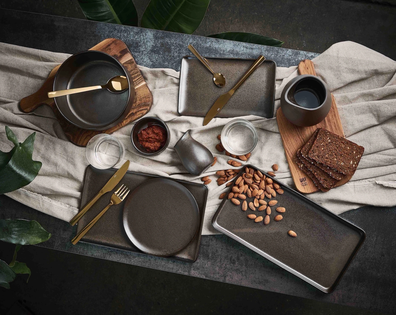 Bruna tallrikar uppdukade på svart bord med jordiga färger