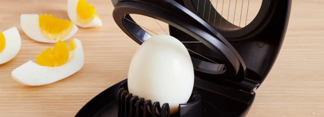 Äggskärare i vart med ägghalvor och ägg som ska delas 