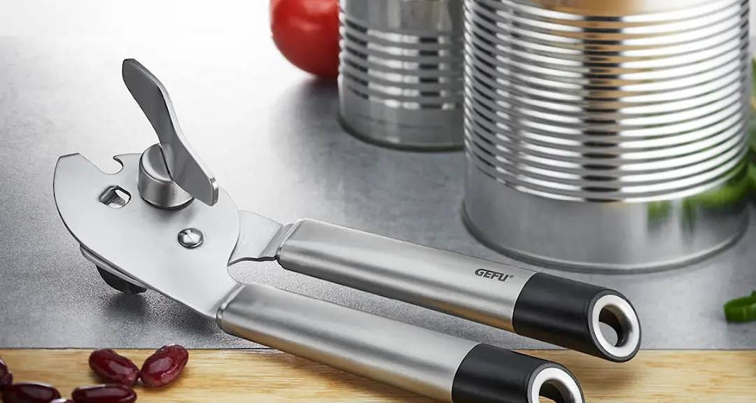 a can opener is sitting on a cutting board next to a can of soup .