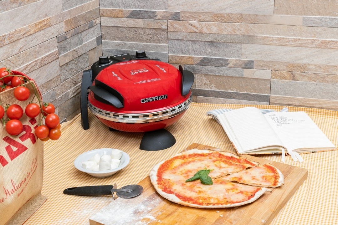 a pizza is sitting on a wooden cutting board next to a pizza oven .