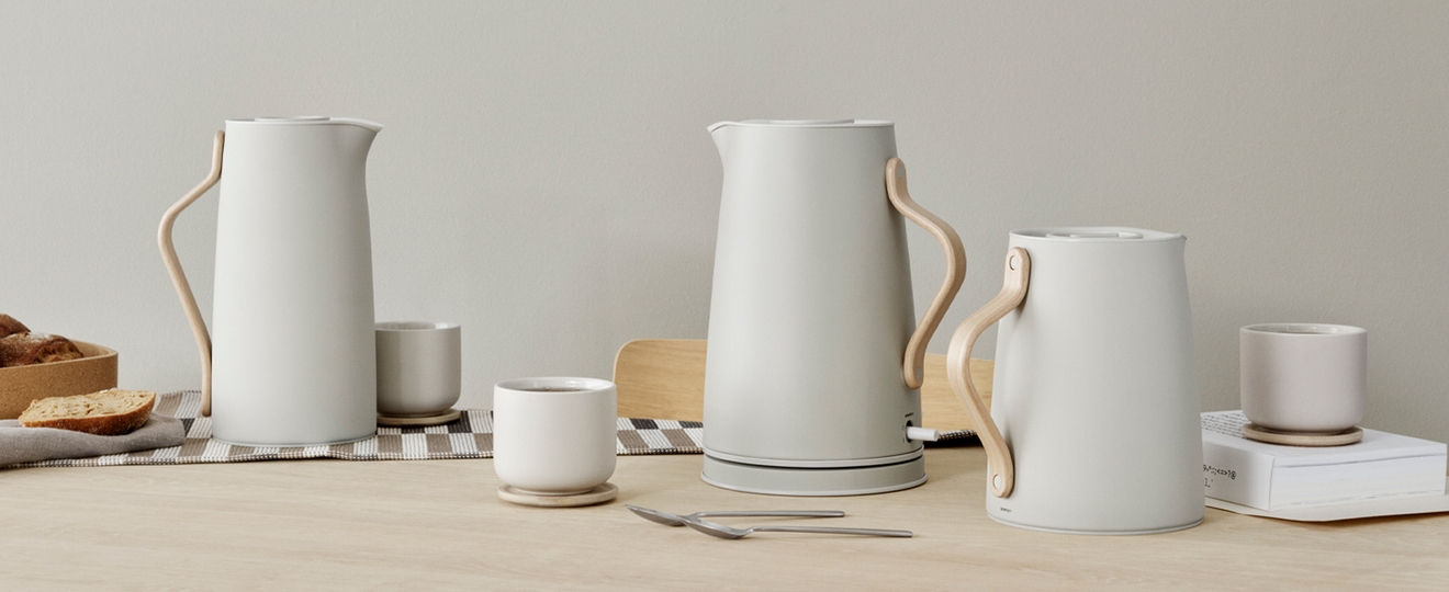 Kolme modernia luonnonvalkoista karahvia vaaleilla puisilla kahvoilla, sekä pieniä kuppeja ja puinen kulho herkkuja.