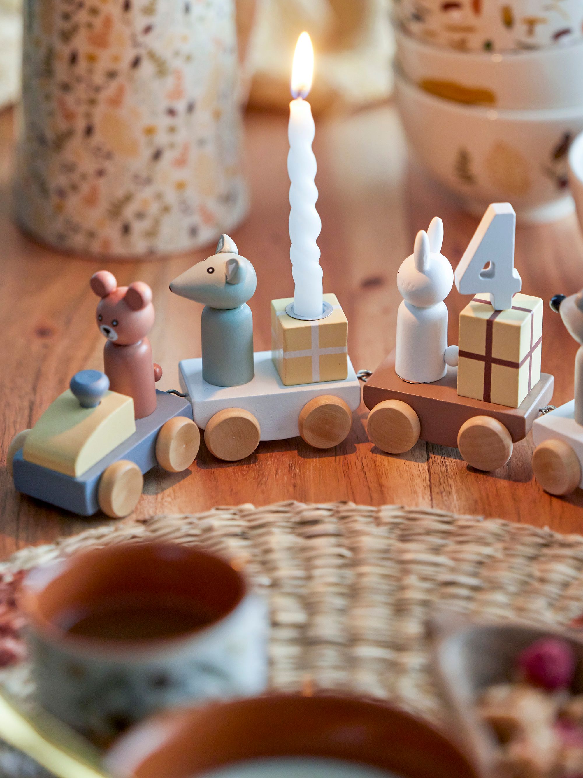 Ett födelsedagståg i trä med ett ljus ovanpå står på ett träbord.