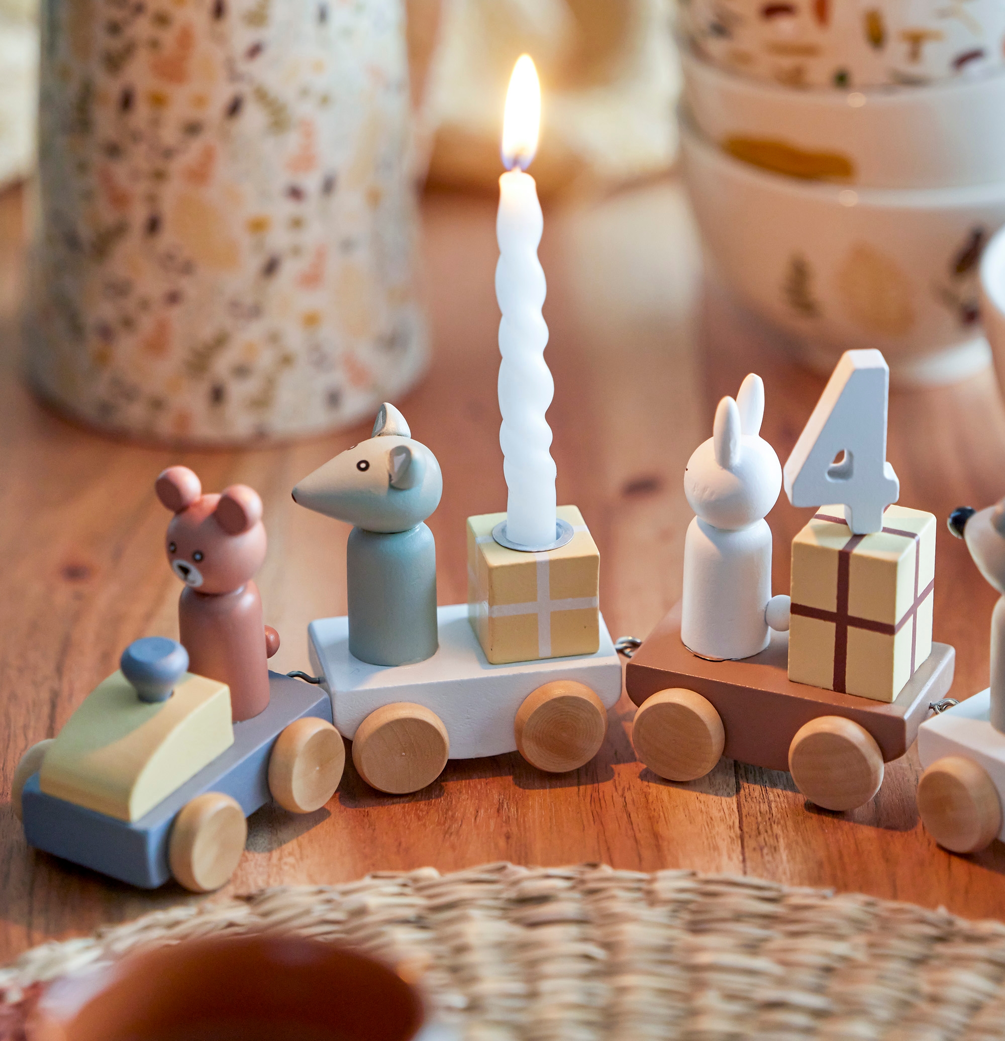 Ett födelsedagståg i trä med ett ljus ovanpå står på ett träbord.