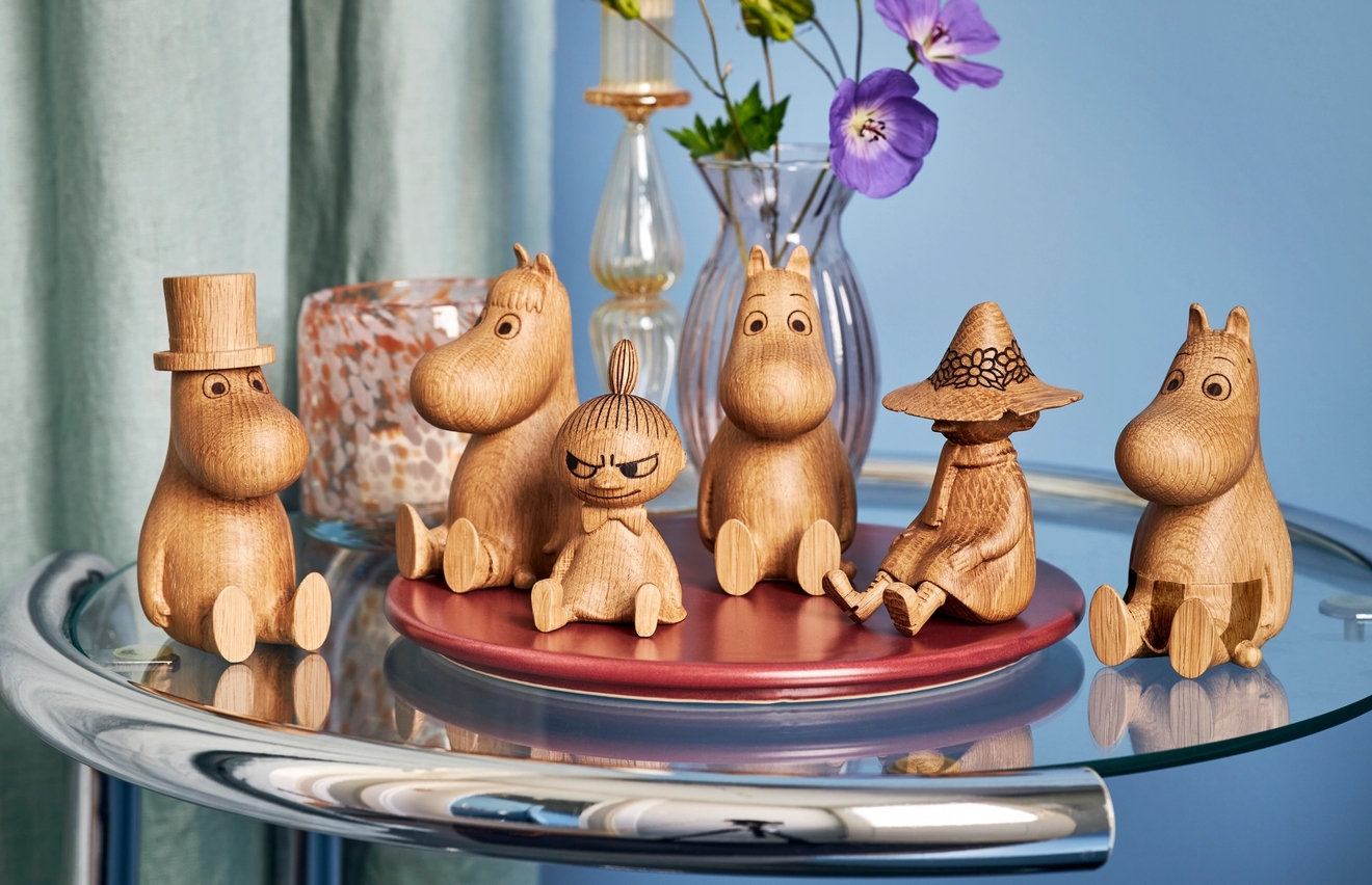 Muminfigurer i trä som sitter på ett bord