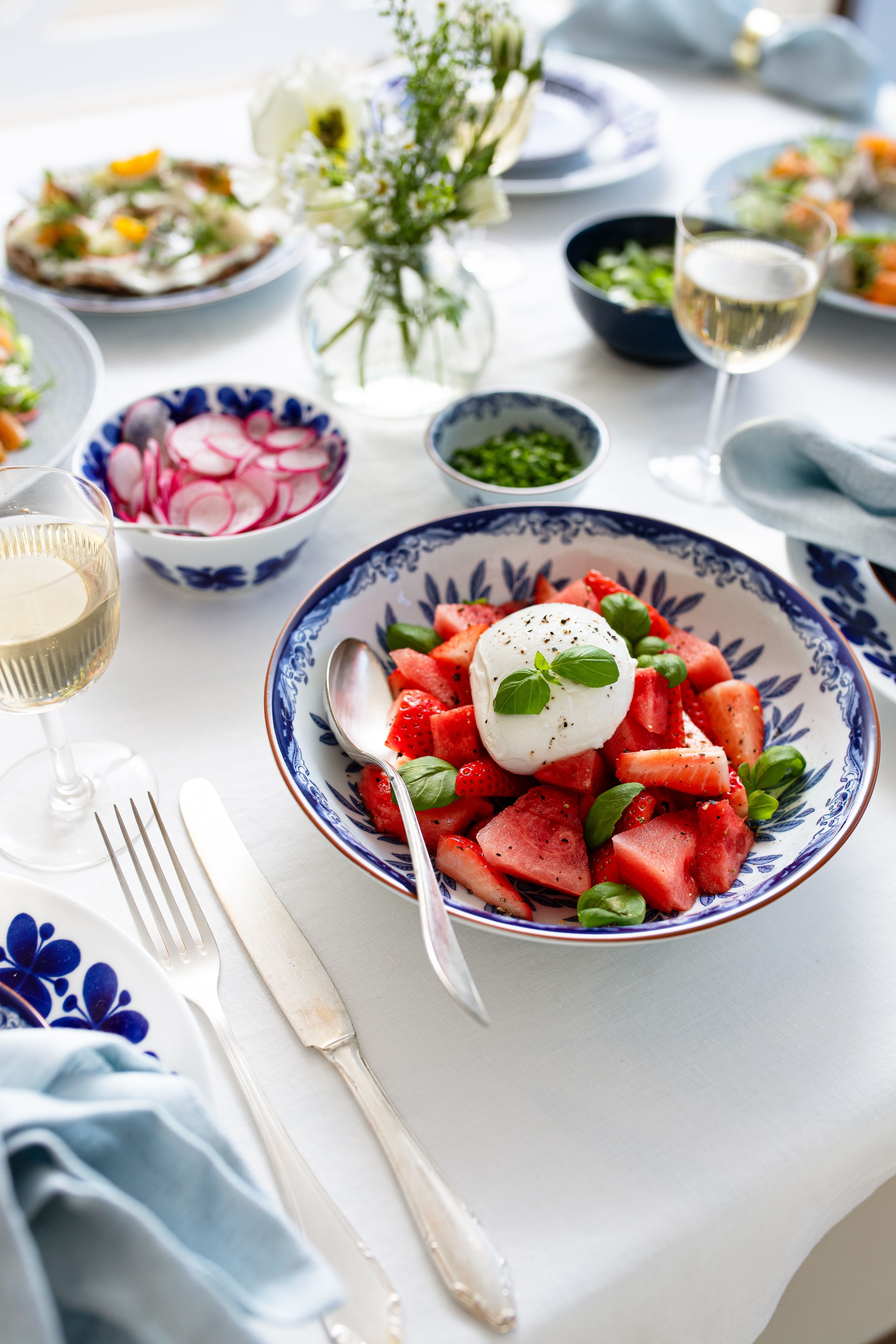 Sommarsallad med vattenmelon, jordgubbar och burrata i en blåvit serveringsskål