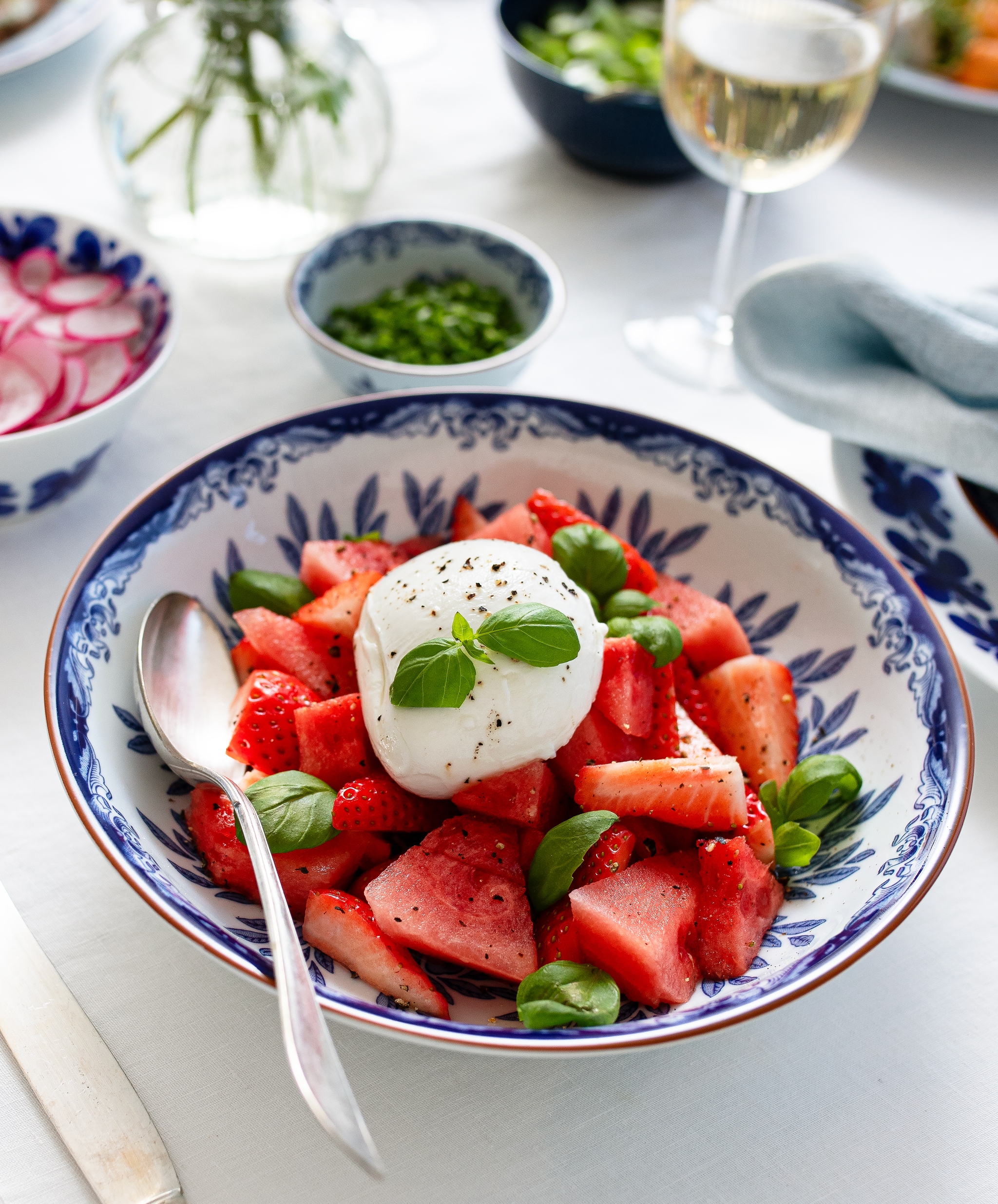 Sommarsallad med vattenmelon, jordgubbar och burrata i en blåvit serveringsskål