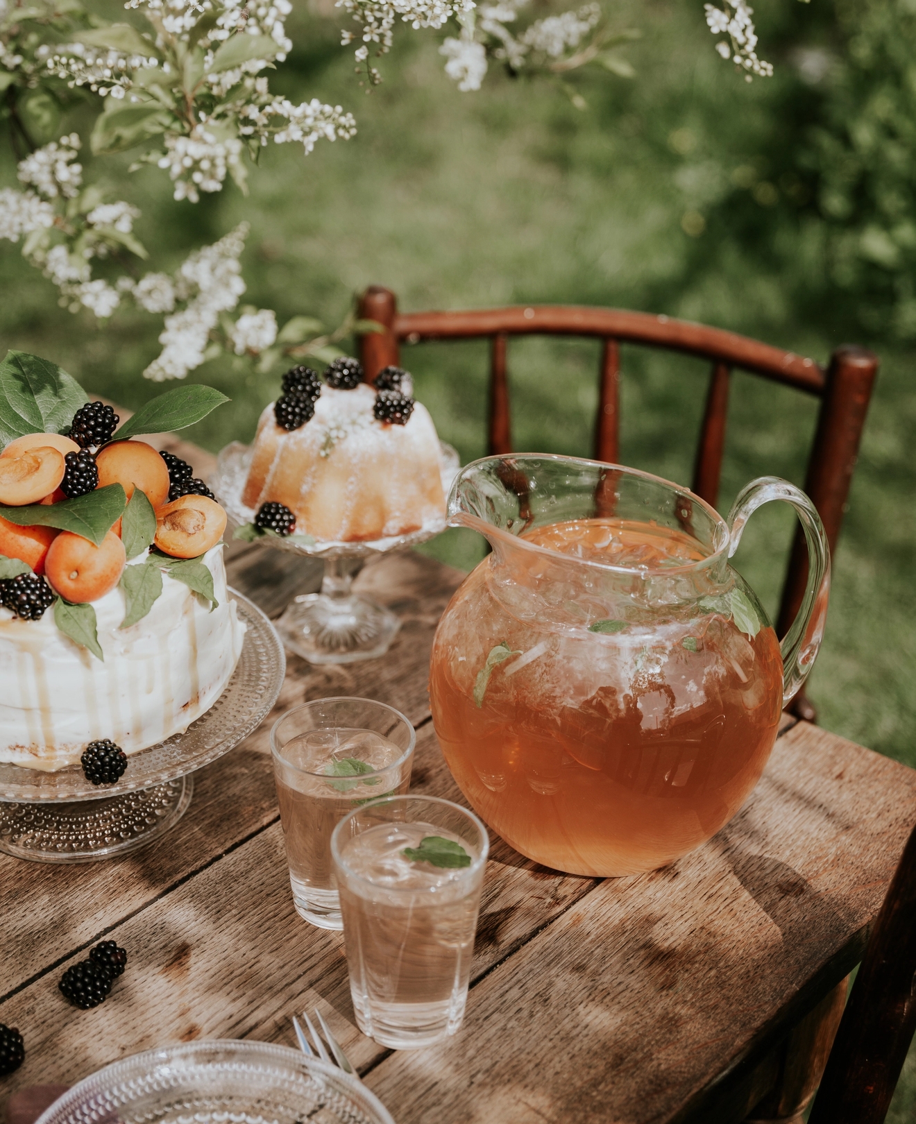 Saftmugge fylt med saft på et bord med en kake i hagen