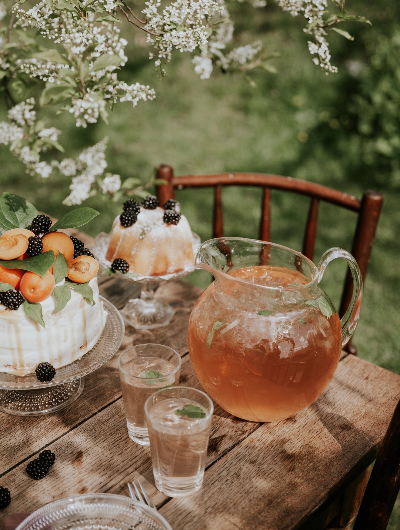 Saftkanna fylld med saft på ett bord med en tårta i trädgården