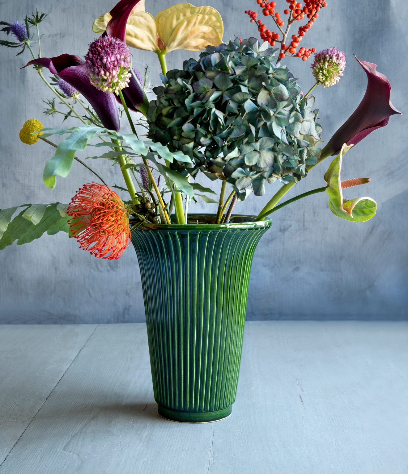 Bergs Potter grön kruka med en färgglad blombukett i