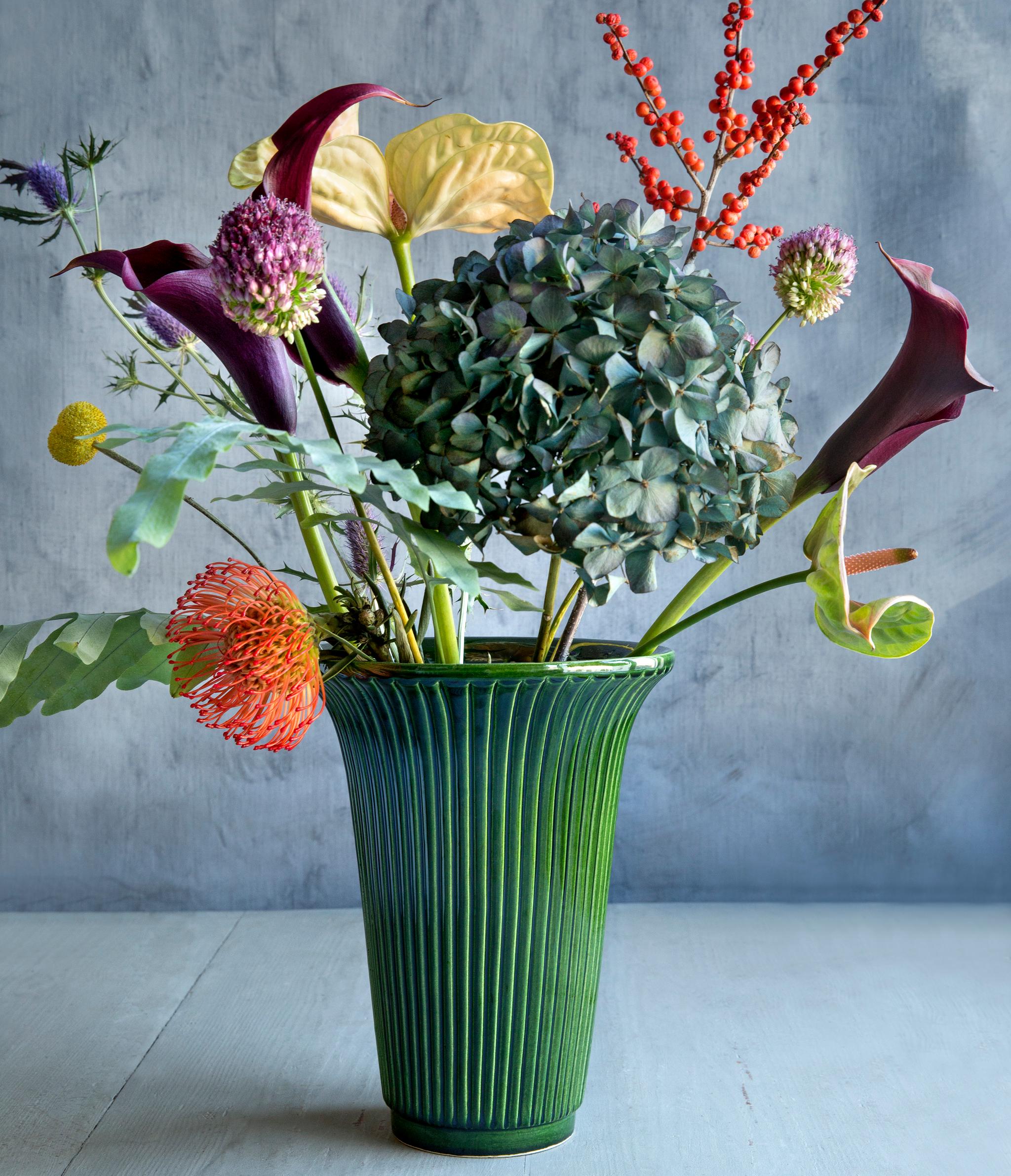 Vihreä maljakko värikkäiden kukkien kera