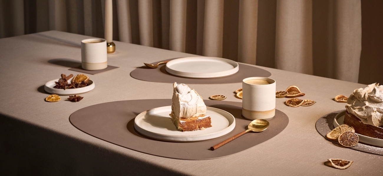 Ett bord dukat med bordstabletter och assietter med kaka på