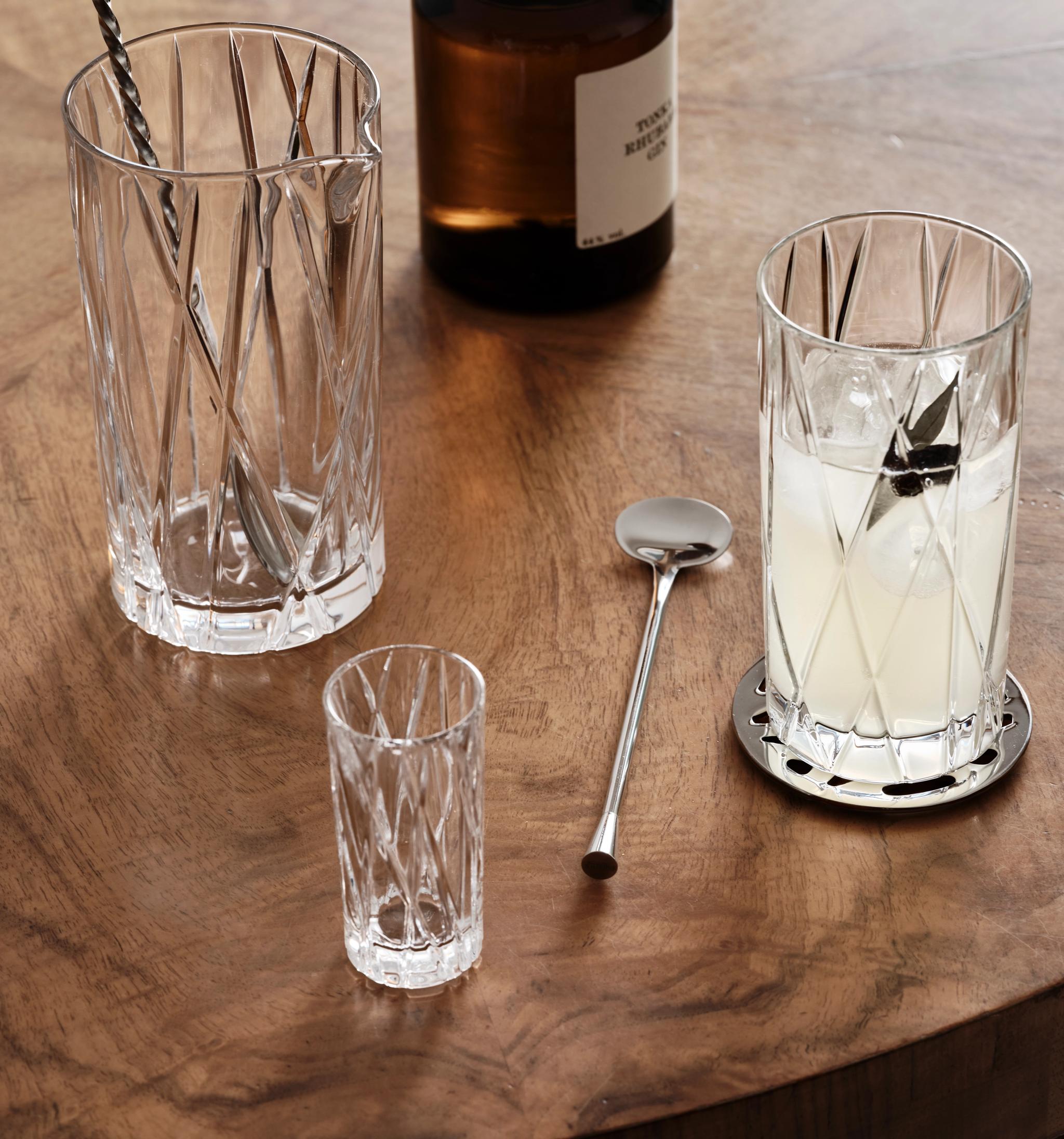 ett glas med en sked i står på ett träbord
