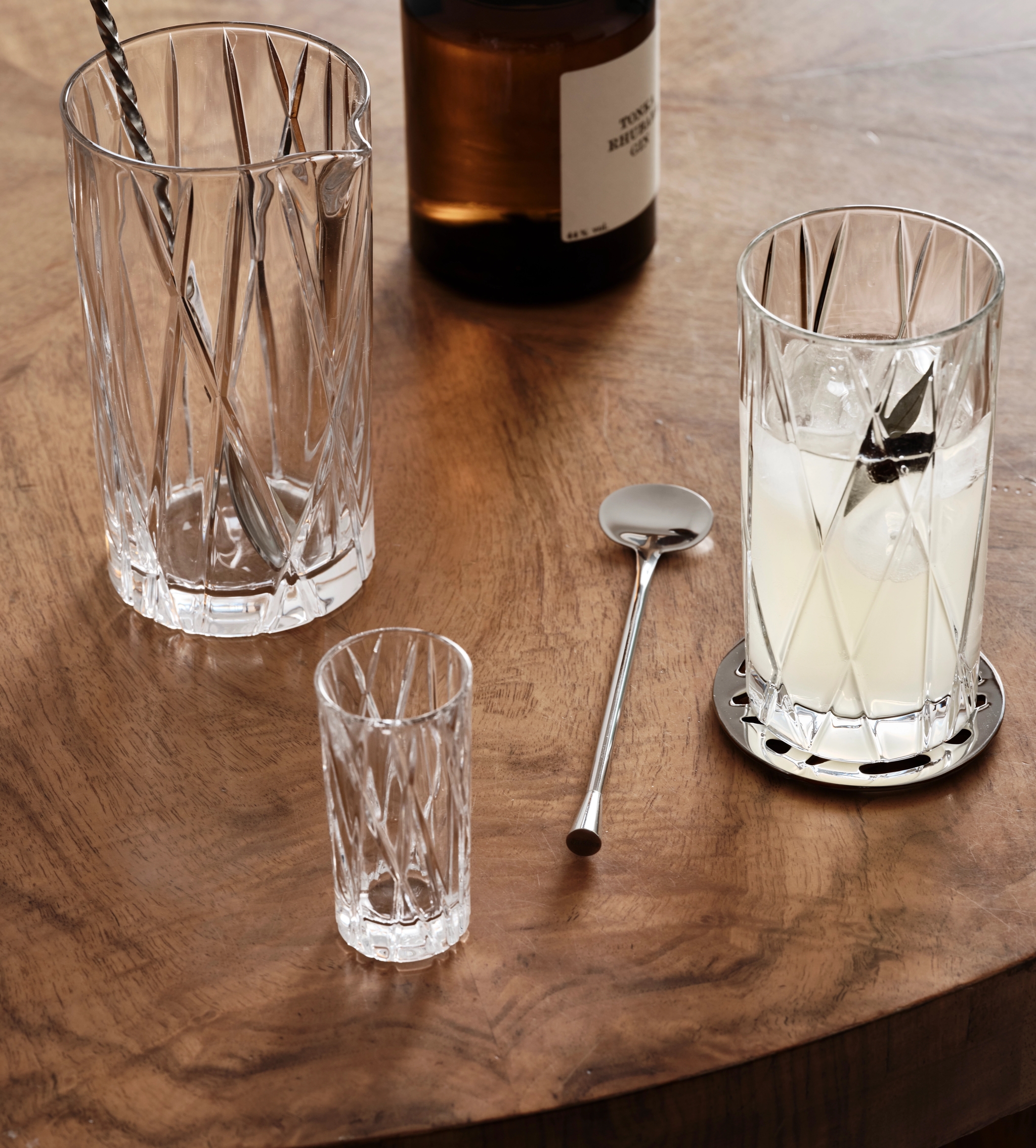 ett glas med en sked i står på ett träbord