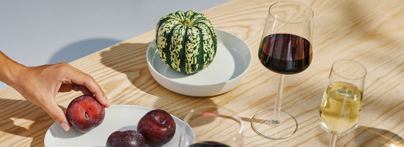 Iittala viinilasit valkoviinille ja punaviinille sekä hedelmät valkosilla lautasilla