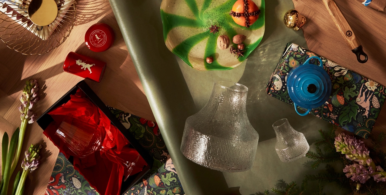 Holiday gifts and kitchenware laid out with festive decor and wrapping.