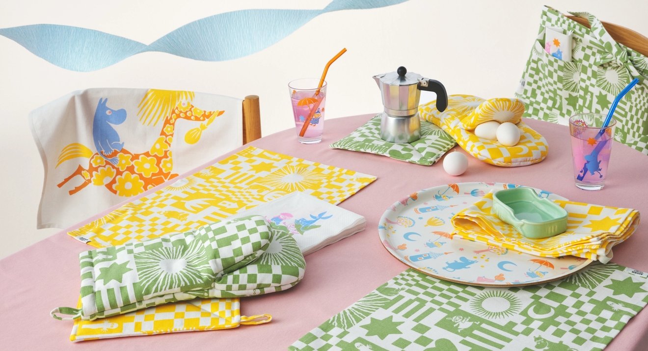 Muumi juhlat kokoelma katetulla pöydällä täynnä pastellivärejä, laseja, servettejä, tarjotin ja pöytätabletit