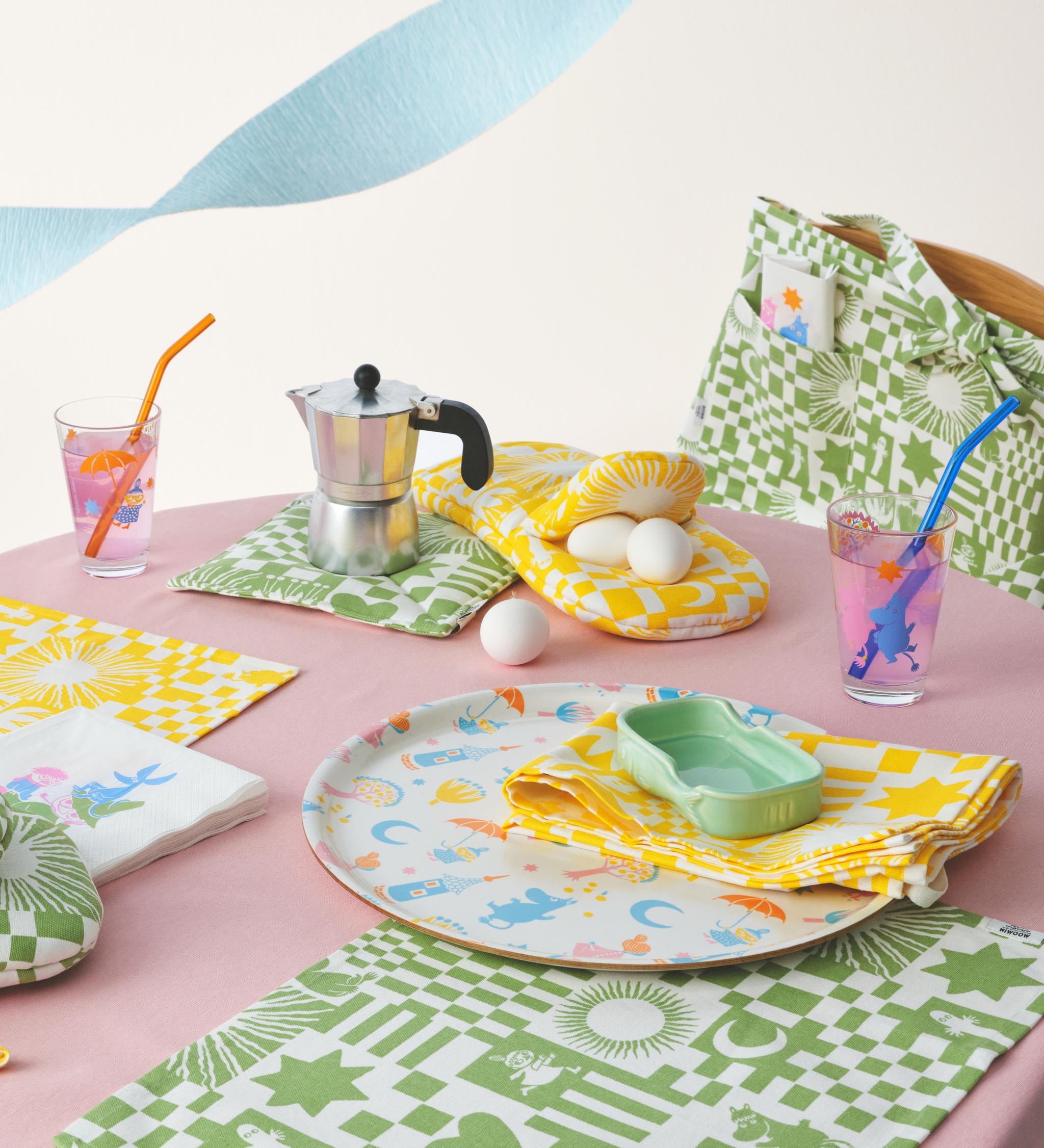 Muumi juhlat kokoelma katetulla pöydällä täynnä pastellivärejä, laseja, servettejä, tarjotin ja pöytätabletit